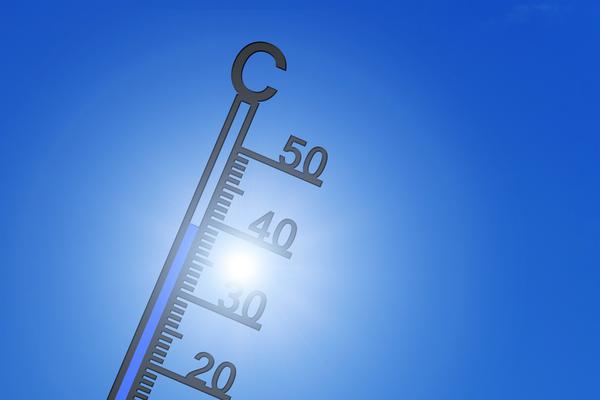 Thermometer vor der Sonne und blauem Himmel