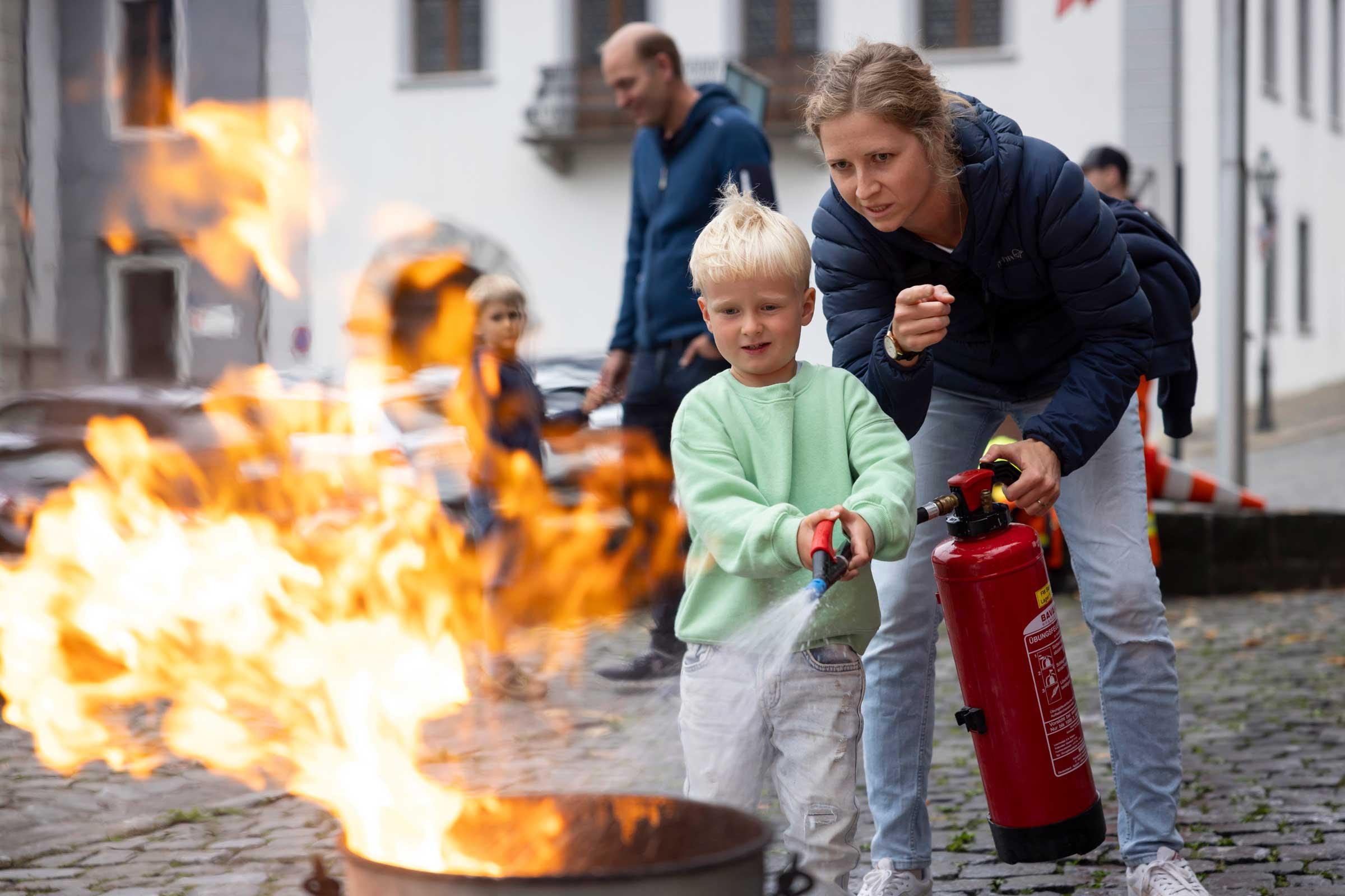 Unter Anleitung der Feuerwehr probieren Gross und Klein den Feuerlöscher aus.