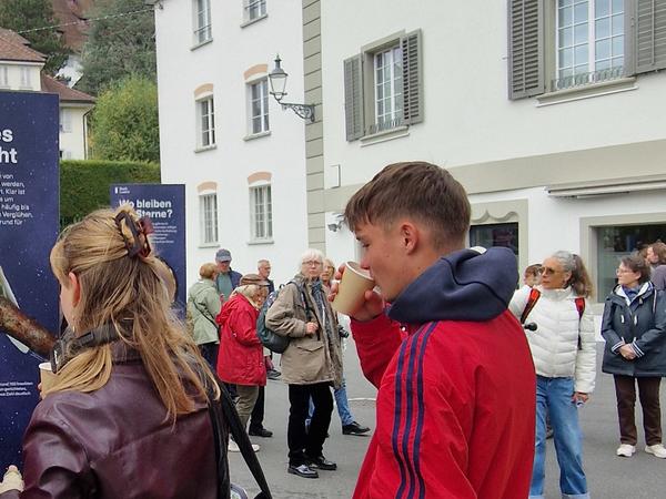 3 Passanten schauen die Ausstellung an