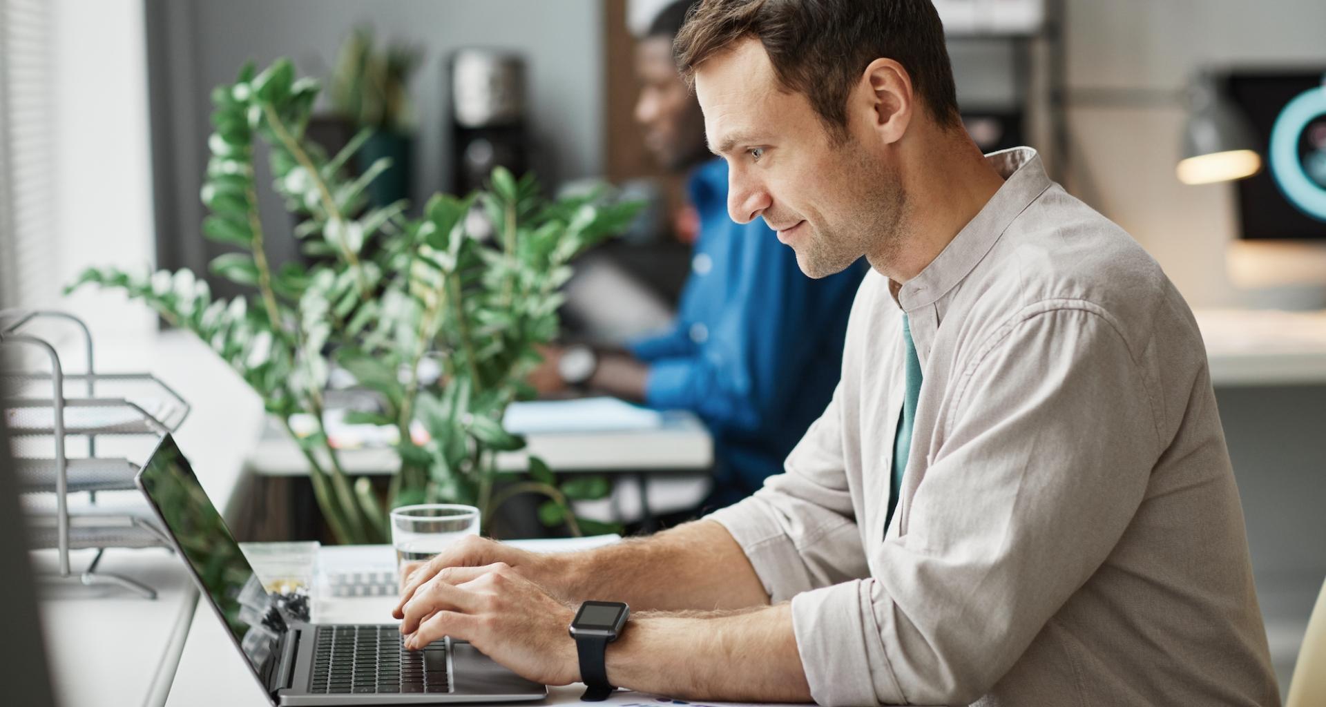 Homme travaillant sur son ordinateur portable, vu de profil