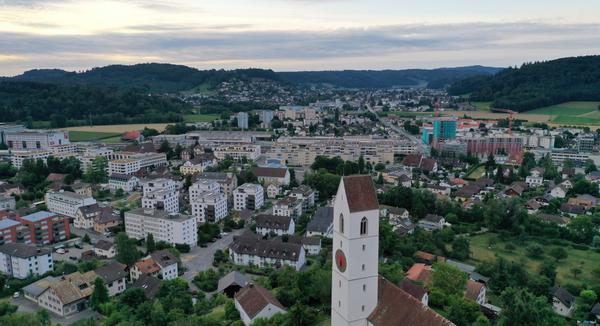 Ein Luftbild der Gemeinde Suhr mit dem Kirchturm der evangelischen Kirche am Fusse des Suhrerchopfs