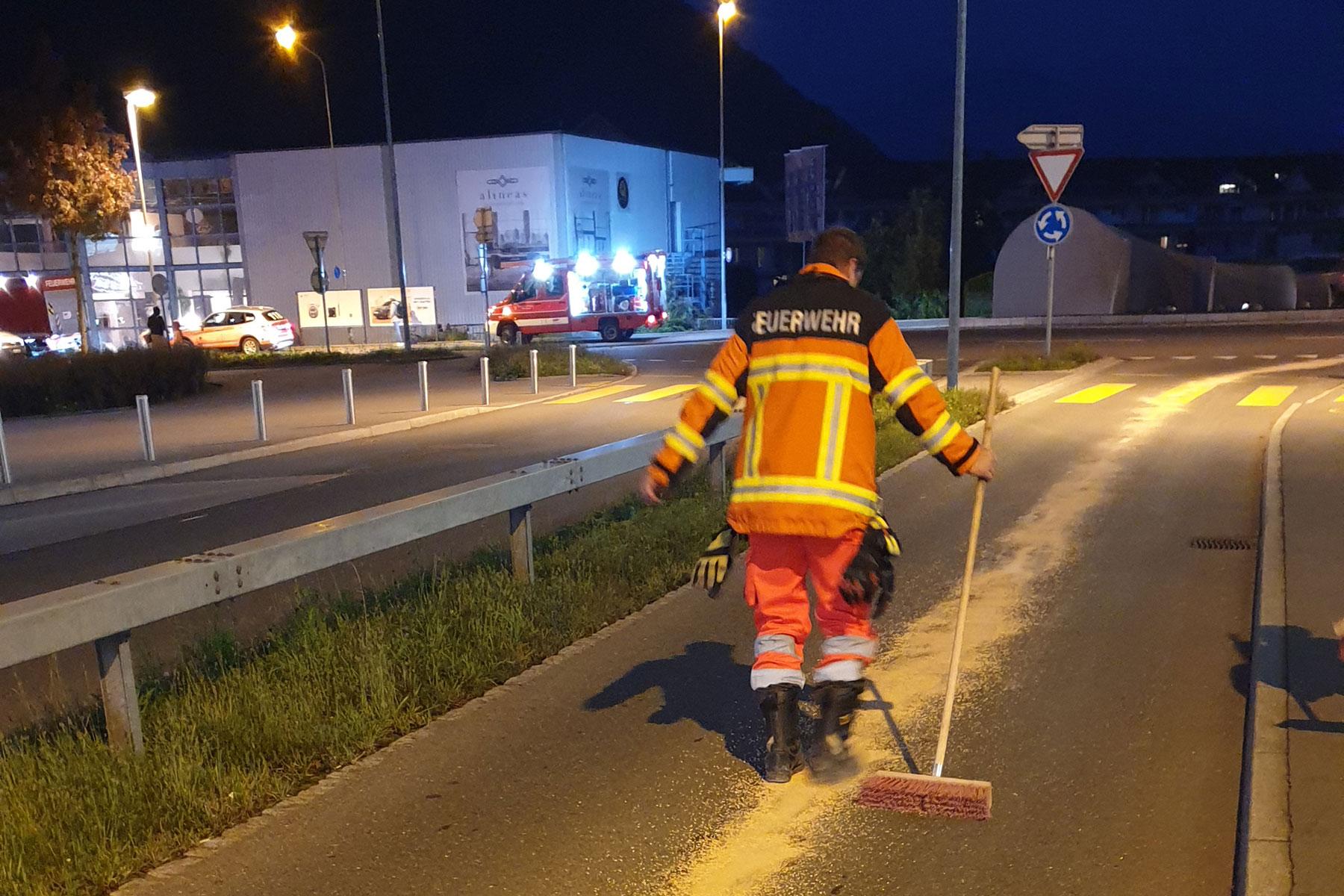 Durch ein Konferenzgespräch aufgeboten beseitigen Feuerwehrleute eine Ölspur auf der Bitzistrasse.