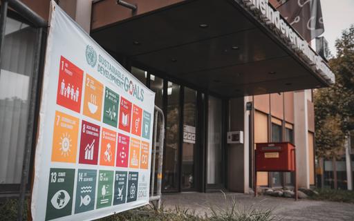 SDG-Flagge vor Verwaltungsgebäude.