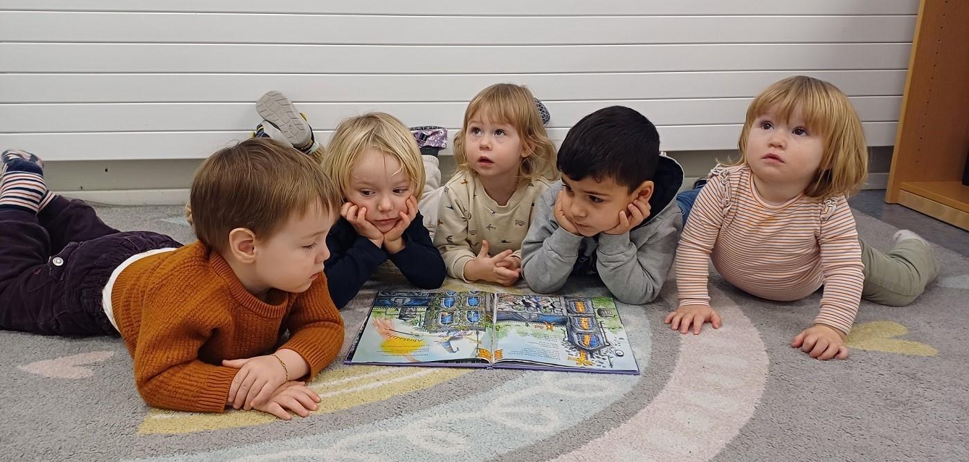 Bild von einer Gruppe Kleinkindern, die ein Buch anschauen