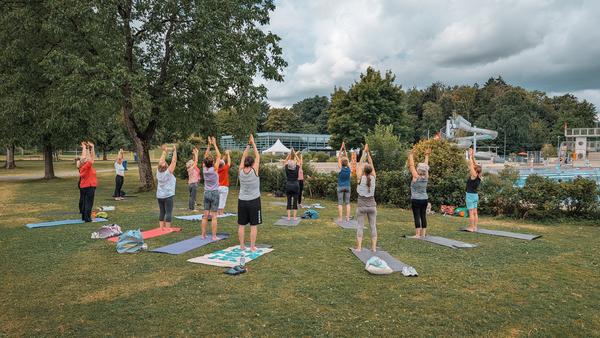 Menschen draussen beim Yoga.