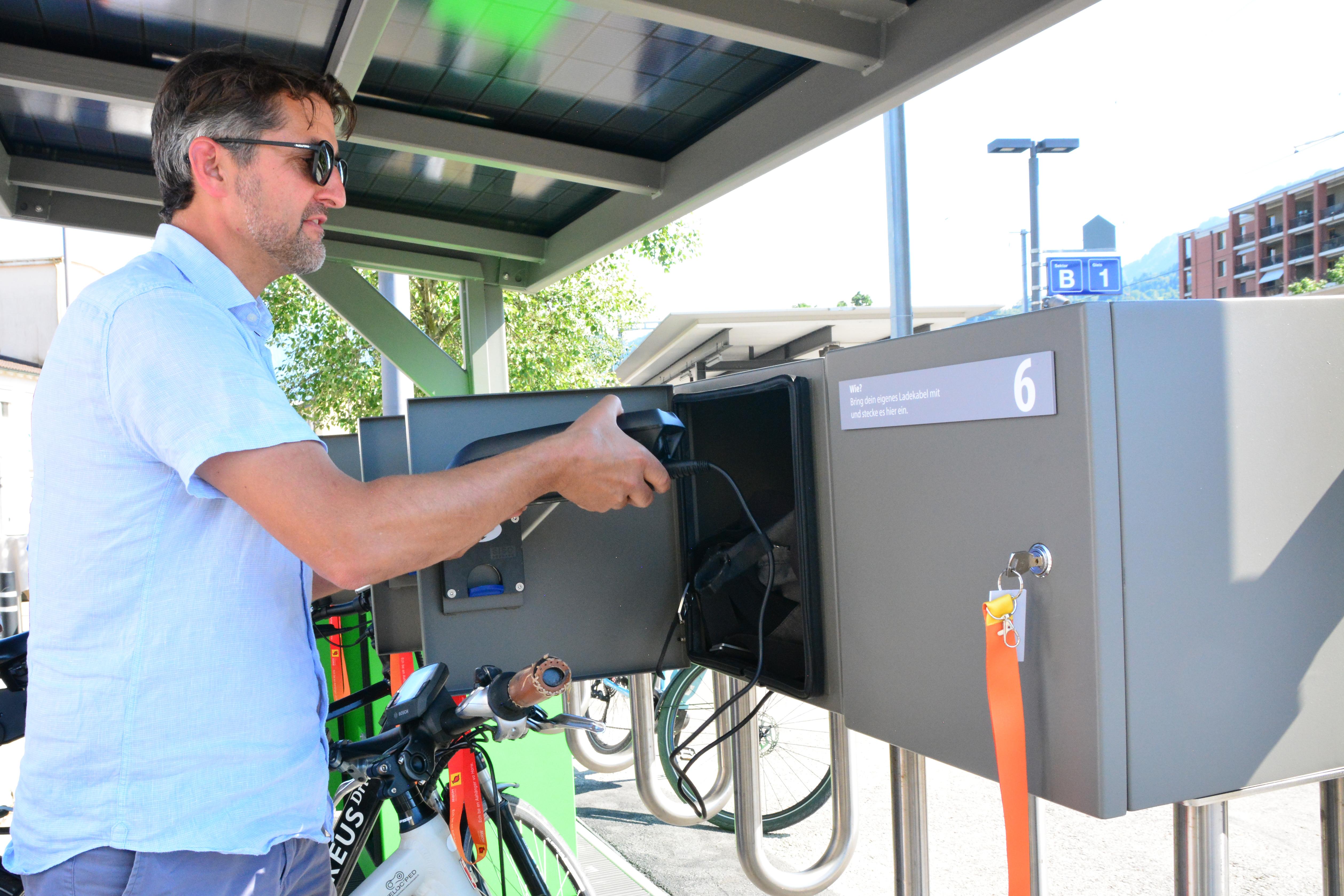Ein Mann schliesst seine E-Bike-Batterie in ein Schliessfach.