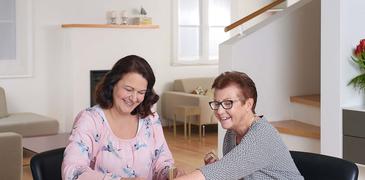2 ältere Damen sitzen an einem Tisch und spielen ein Spiel
