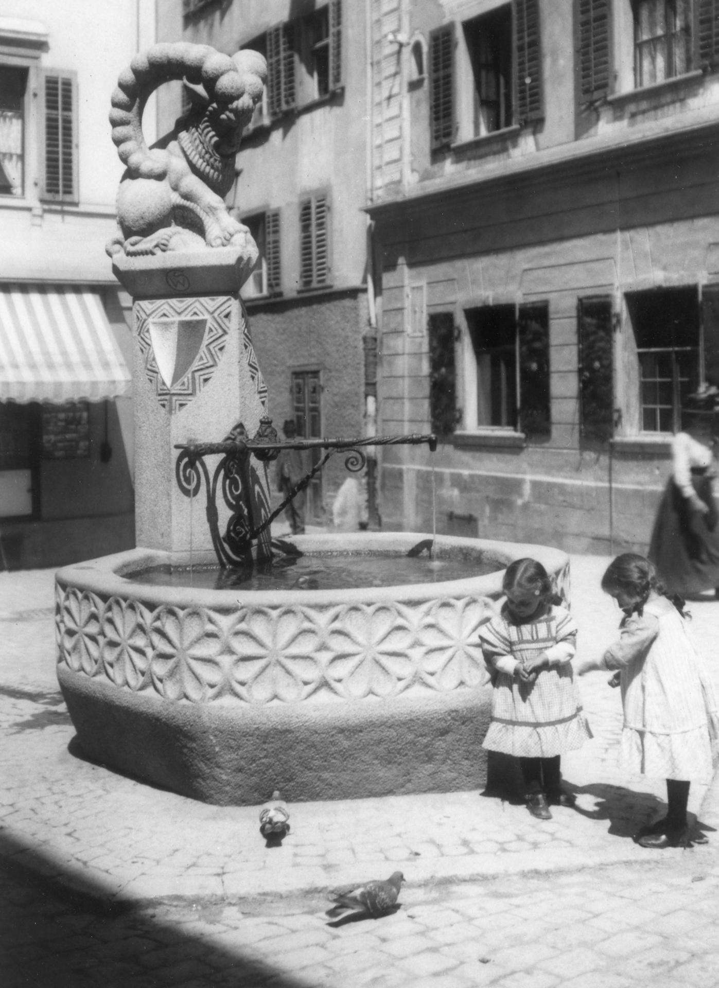 Fotografie zweier
Mädchen beim Majoranbrunnen. Der
Brunnen stammt von 1912 und wurde von
Bildhauer Wilhelm Schwerzmann erstellt.
(StadtAC, F 07.003.013, Fotograf unbekannt,
ca. 1913–1916).