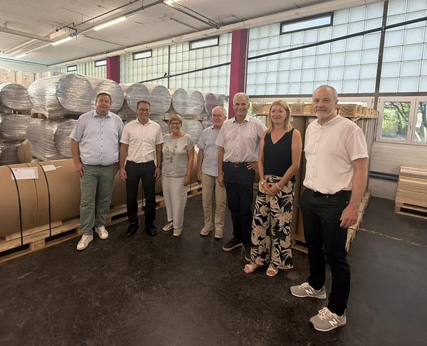Legende: CEO Walter Schläpfer (3. von rechts) erklärte den Gemeinderätinnen und Gemeinderäten, wie zum Beispiel Backtrennpapier entsteht, auf dem der Teig nicht klebt.