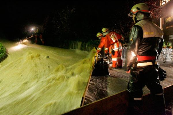 Mit Brettern und Sandsäcken schützt die Feuerwehr die Häuser.