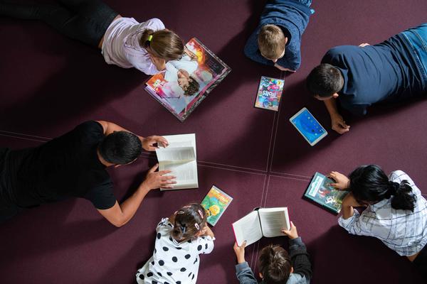 Mann und Kinder mit Büchern und Zeitschriften