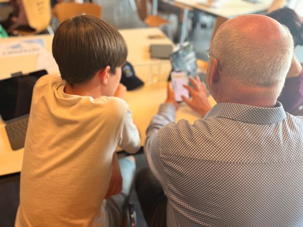 Jugendlicher hilft Senior bei Einstellungen am Smartphone