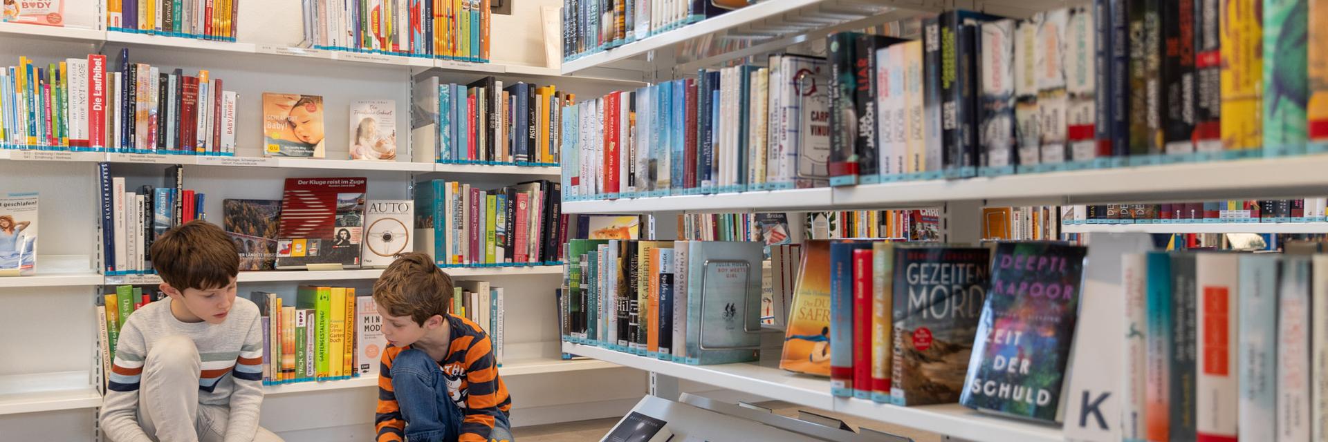 Zwei Buben schauen Bücher an