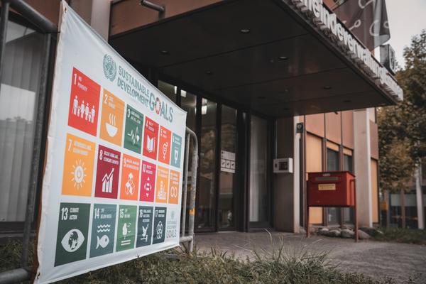 SDG-Flagge vor Verwaltungsgebäude.