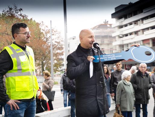 Stadtrat Stefano Kunz übergibt Carlos Pighin, Bereichsleiter Gas- und Wasserversorgung, den symbolischen Schlüssel zum Brunnen.