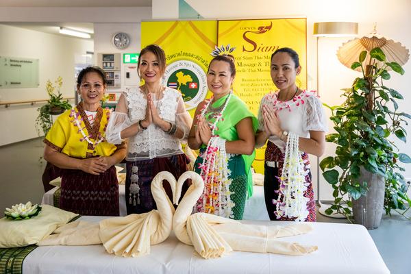 Vier thailändische Frauen begrüssen Besucherinnen und Besucher mit dem Gruss Sawasdee und der Geste Wai.