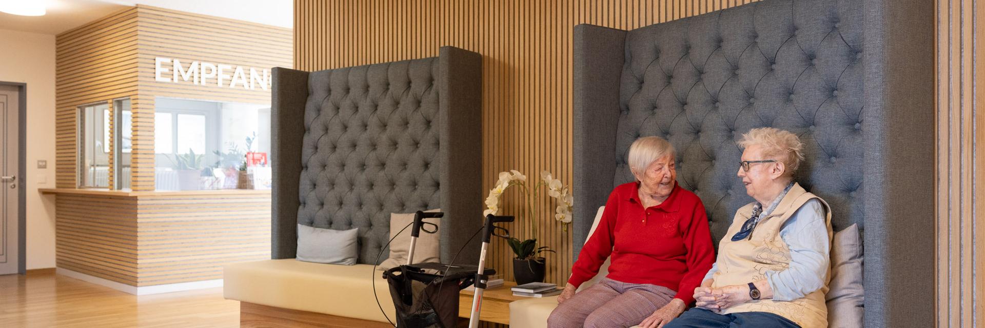 Zwei ältere Frauen unterhalten sich auf einer Bank