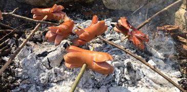 Cervelats werden über einem Feuer gebraten