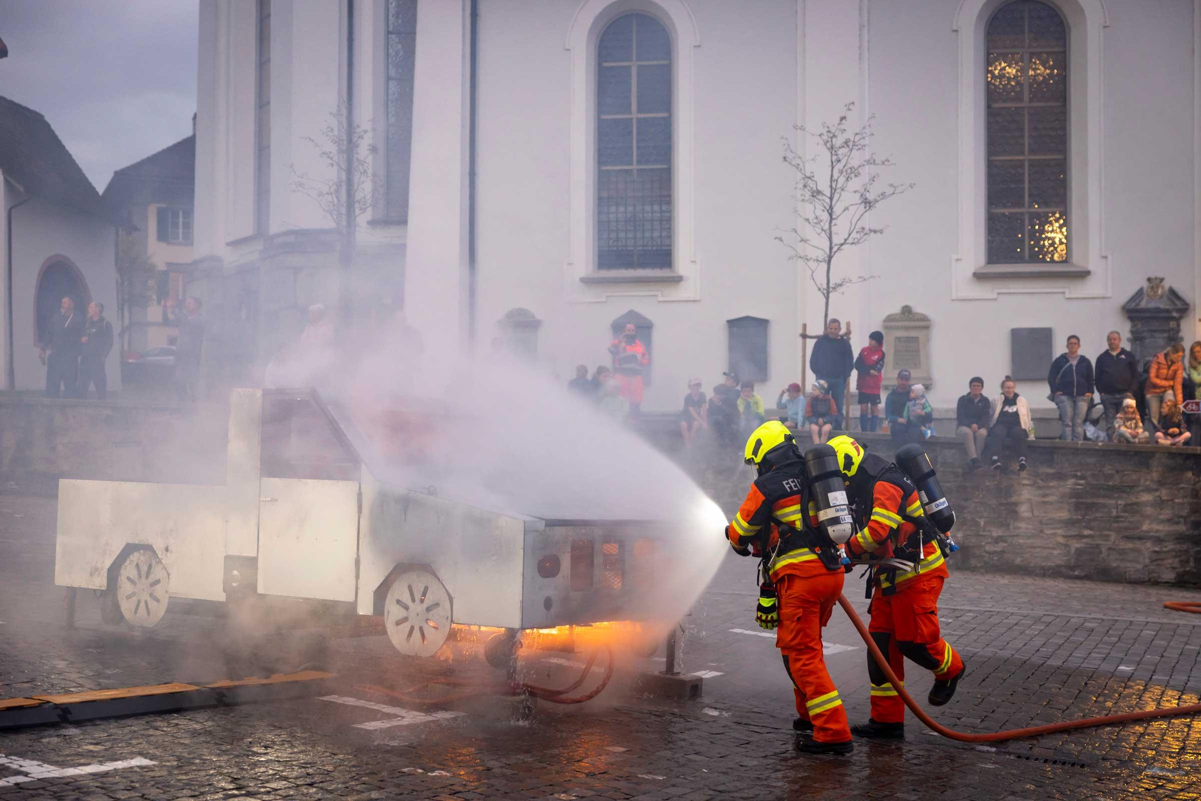 Feuerwehrleute löschen den Autobrand.