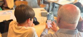 Jugendlicher hilft Senior bei Einstellungen am Smartphone