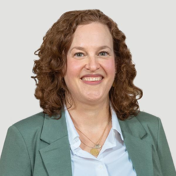 Eine Frau mit grüner Bluse und freundlichem Lächeln
