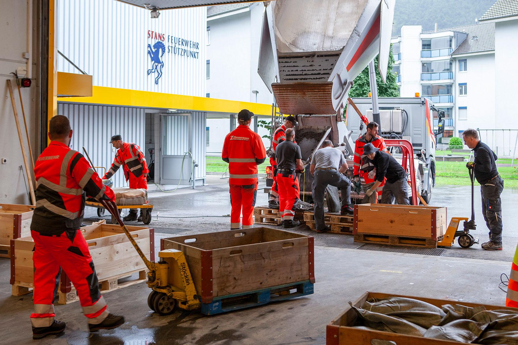 Feuerwehrleute füllen Sandsäcke und geben diese an die Bevölkerung ab.