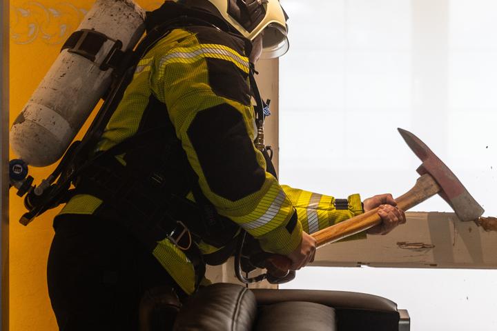Bild eines Feuerwehrmannes mit einem Werkzeug der gerade eine Tür öffnet