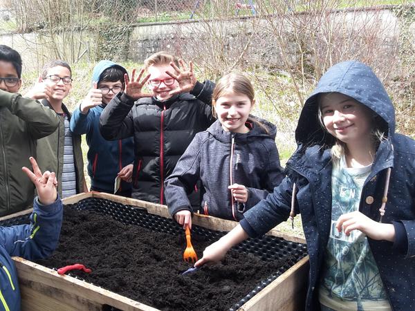 Kinder posieren hinter Hochbeet