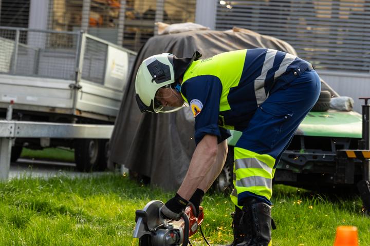 Bild eines Feuerwehrmannes mit einem Seitenschleifer mit dem er ein Stück Metall schneidet