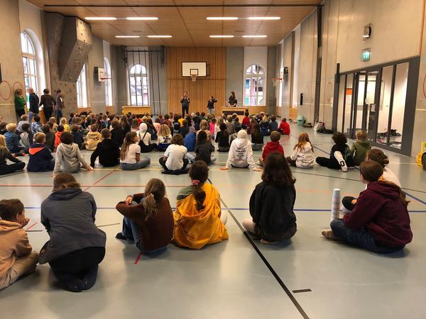 Schüler sitzen auf dem Boden in der Turnhalle