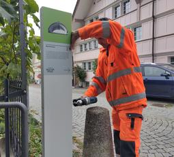 Ein Werkhof-Mitarbeiter schraubt die neue Stele in der Bachstrasse an.