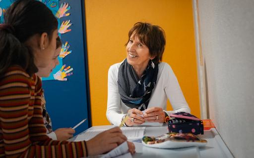 Eine Seniorin mit zwei Kindern am Pult.