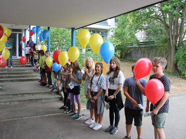 Kinder stehen mit Ballons Spalier